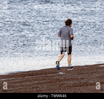 A man jogging on the beach at Fortress, Black Isle, Ross and Cromarty, Scotland, United Kingdom. Stock Photo