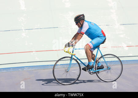 Older Cyclist riding round a velodrome Stock Photo