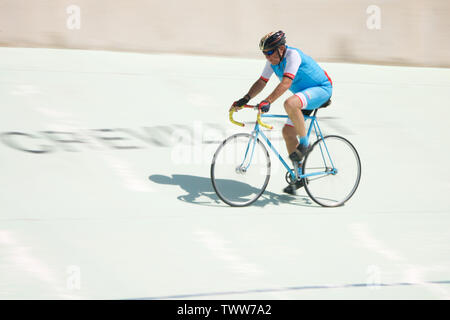 Older Cyclist riding round a velodrome Stock Photo