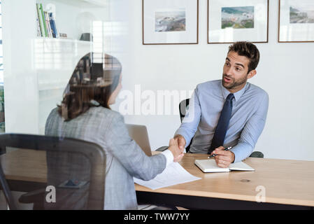Manager shaking hands with an employee at his office desk Stock Photo