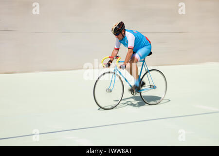 Senior citizen riding a bicycle around a velodrome Stock Photo