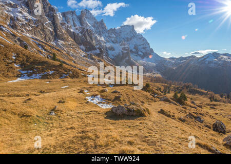 Pale di San Martino mountain range in Italy. Direct sunlight and sunrays hitting the alpine meadow in an autumn day. Fall colours in the mountains. Stock Photo