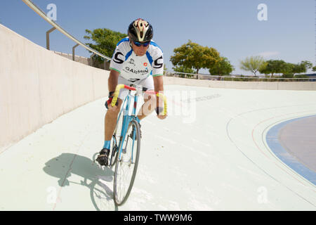 Senior citizen riding a bicycle around a velodrome Stock Photo