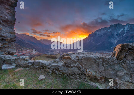Sky on fire at sunset. Painted, vivid sky with colorful clouds, sunset in the mountain valley. Val Camonica sunset. Sun setting behind the mountains. Stock Photo