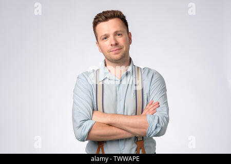 Man in casual clothes and suspenders looking camera, holding hands crosse Stock Photo
