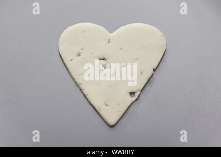 Thin slice of hamburger cheese in the shape of a heart on a gray plate Stock Photo