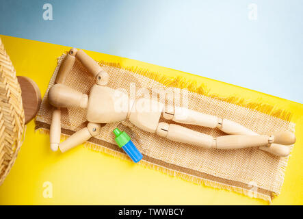 Wooden dummy on yellow as sand beach and blue as water. Concept travel to beach. View from above. Stock Photo
