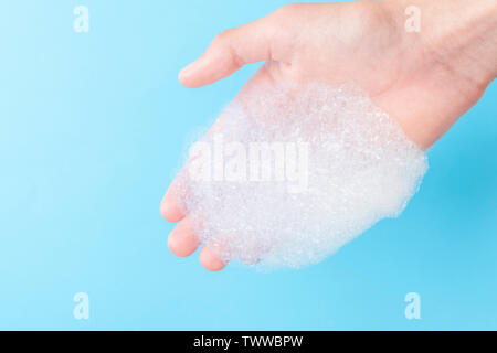 Foam with large bubbles in his hand on a blue background. The concept of active cleaning in the apartment Stock Photo