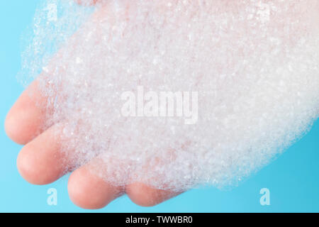 Foam with large bubbles in his hand on a blue background. The concept of active cleaning in the apartment Stock Photo