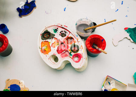 Palette and paint brushes. Cans with paints and water on the table. Watercolor painting. The concept of drawing, creativity and education. The Stock Photo
