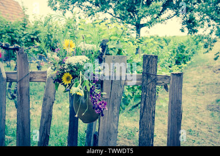 flowers in pot hanged over wooden fence Stock Photo