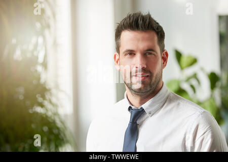 Portrait of middle aged man wearing shirt and tie while standing indoor and looking at camera. Stock Photo