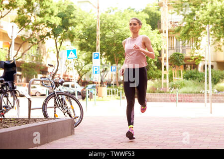 Full length shot of young woman running in the city. Stock Photo
