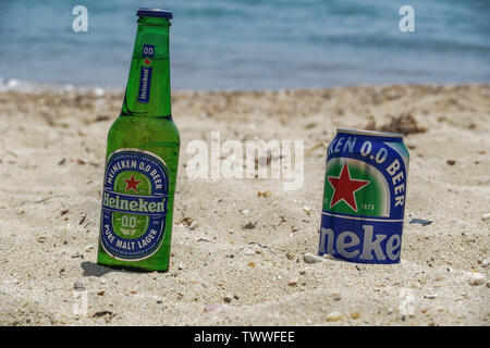 Heineken zero alcohol beer bottle & can on sandy beach. Non-alcoholic lager beer on 33cl glass bottle & can partly submerged on a beach at a sunny day Stock Photo