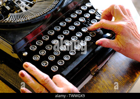 Close-up of a female's hand typing on an old-fashioned typewriter - John Gollop Stock Photo