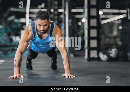 Concentrated muscular guy doing push up exercises Stock Photo