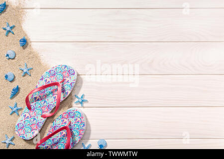 Summer background. White Wooden background with flip flops, sand and seashells. Vacation or beach concept Stock Photo