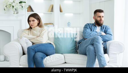 Relationship Problems. Couple Sitting On Different Sides Of Couch Stock Photo