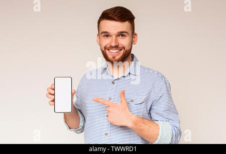 Smiling millennial man holding latest slim cellphone Stock Photo