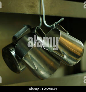kitchen utensils, pans and sauce pots hanging with hooks Stock Photo