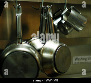 kitchen utensils, pans and pots hanging with hooks Stock Photo