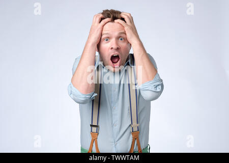 Shocked face of young european man in blue shirt and suspenders Stock Photo