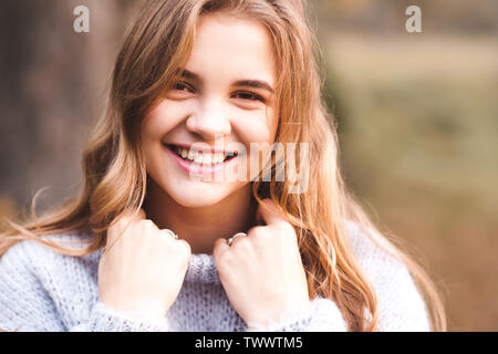 Happy teen girl 14-16 year old wearing cozy knitted sweater outdoors. Looking at camera. Stock Photo