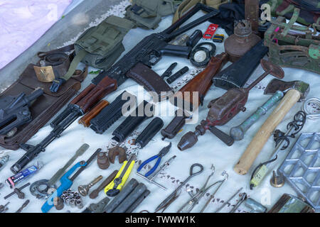 Antique antiques are sold at a flea market.A copy of the Kalashnikov assault rifle on the counter along with various tools Stock Photo