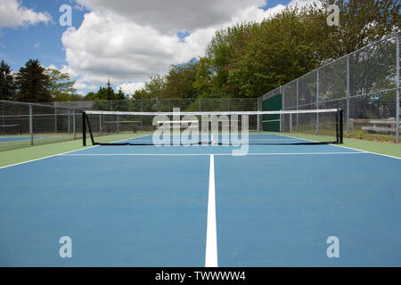 Blue tennis court with black net empty on a summer day Stock Photo