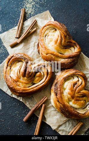 Baked fresh fragrant cinnamon buns. Traditional homemade pastries on dark background. Rustic style. Stock Photo