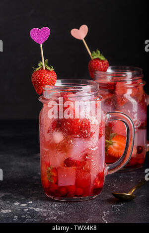 Strawberry lemonade with ice in jar on dark background. Concept of summer drinks for couple Stock Photo
