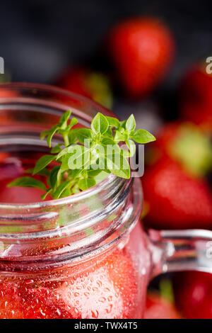 Basil on jar with strawberry drinks with berries around. Concept of summer background Stock Photo