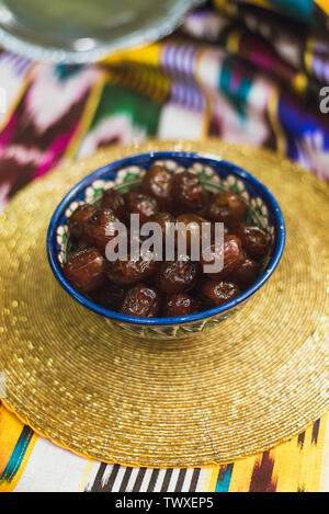 Eastern sweets in the dishes of the Middle East with gold and on Tatar cloth. Dried sweet dates lie in a plate on a golden tablecloth. Stock Photo