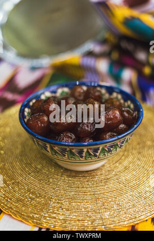 Eastern sweets in the dishes of the Middle East with gold and on Tatar cloth. Dried sweet dates lie in a plate on a golden tablecloth. Stock Photo