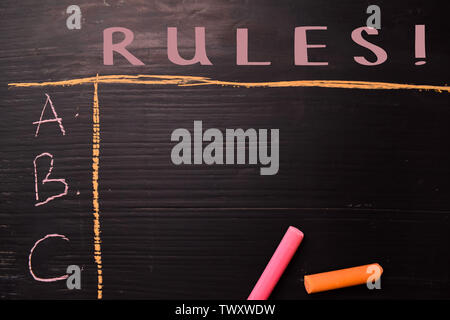 Rules! written with color chalk. Supported by an additional services. Blackboard concept Stock Photo