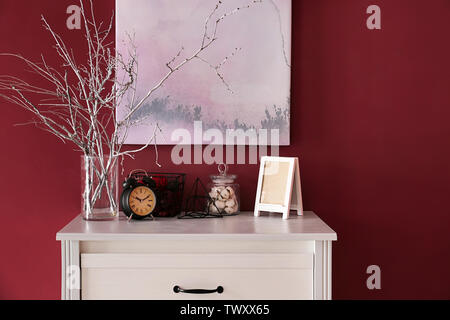 Chest of drawers with stylish decor near color wall in room Stock Photo