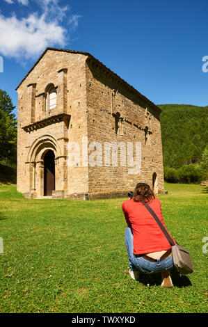 Young woman photographing the XI century romanesque church of Santa María de Iguácel in Garcipollera valley (Larrosa, Huesca, Aragón, Pyrenees,Spain) Stock Photo