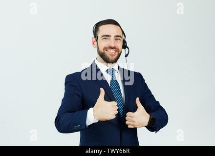 Portrait of cheerful confident handsome young male support operator in headset showing thumbs-up Stock Photo