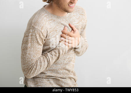 Young man suffering from chest pain on white background Stock Photo