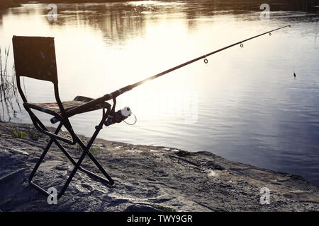 Camping chair with fishing rod at riverside on sunny dayの素材  [FY310206085742]