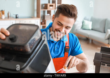 Man repairing coffee machine in kitchen Stock Photo