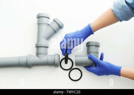 Plumber working with drain pipe on white background Stock Photo