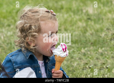 A young infant girl enjoys a delicious ice cream on a summer day Stock Photo
