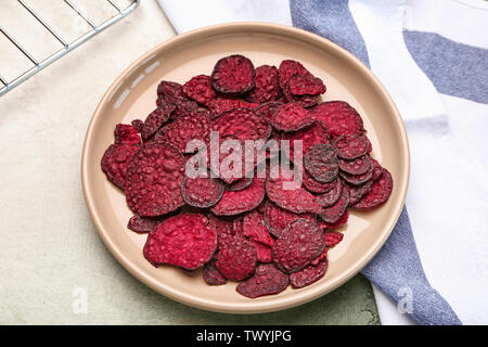 Plate with tasty beet chips on table Stock Photo