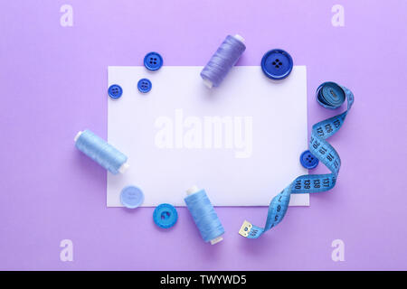 Set of sewing threads with accessories and sheet of paper on color background Stock Photo