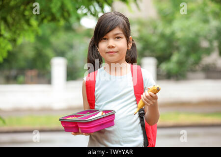 Little schoolgirl with lunch box outdoors Stock Photo