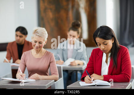 Group of adult students taking notes in class during training course on business and management, copy space Stock Photo