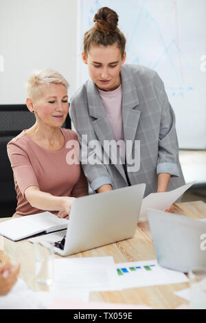 Portrait of two contemporary businesswomen using laptop while discussing project development, copy space Stock Photo