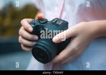 Photographer hands holding a digital camera, focusing and taking photos, macro closeup Stock Photo