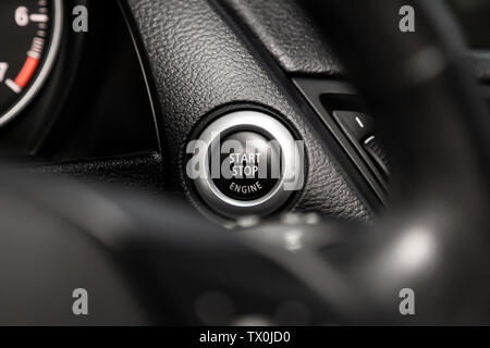 Car engine push start stop button ignition remote starter. Car dashboard:  black engine start stop button, car interior details. Soft focus Stock Photo